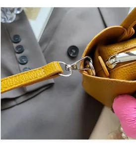 Detail of silver metal hook and zipper on yellow lychee texture leather bucket bag