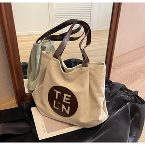 Detail view of large canvas tote bag with brown leather handles and TELN embroidery