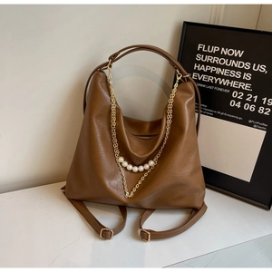 Detail of brown PU leather tote bag featuring gold chain and white pearl embellishments