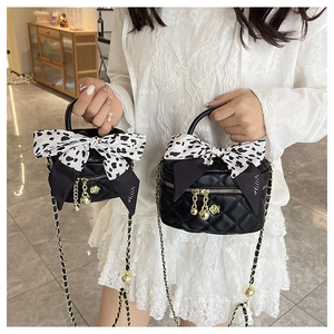 Close-up of black quilted mini bags with leopard bows and gold chain straps