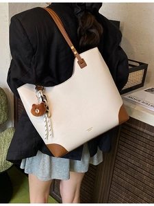Large beige tote bag with brown leather trim and cute bear charm shown on model