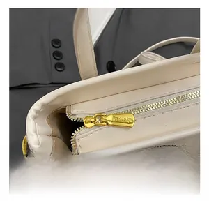 Detailed view of premium gold-tone metal zippers and hardware on cream bucket bag