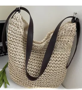 Detail of woven straw tote bag featuring brown leather handles and hollow knit texture