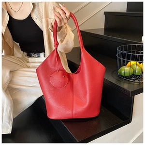 Close-up of a vibrant red tote bag with pebble leather texture and matching mini coin purse