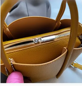Close-up of smooth silver zipper and lychee grain leather on yellow bucket handbag