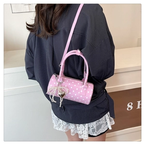 Détail du sac cylindre rose à pois avec nœud en perles et breloques en cœur