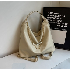 Detail of cream pleated tote bag featuring large pearls and gold chain link accents
