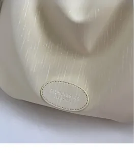 Macro detail of beige tote bag showing sparkling texture and embossed leather patch