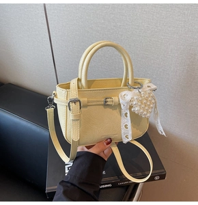 Detail der hellgelben Beuteltasche mit PU-Textur, Metallschnalle und Perlen-Herzanhänger