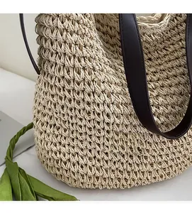 Detail showing handwoven texture of beige straw tote bag with brown leather strap