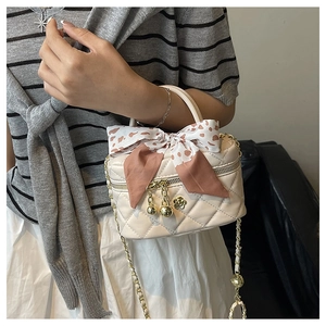 Close-up of cream quilted box bag with leopard silk scarf and gold chain strap