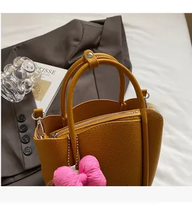 Detailed shot of yellow lychee leather bucket bag with a pink bow and metal zipper