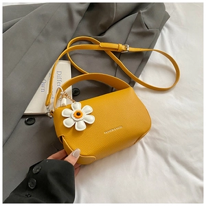 Detail of yellow lychee texture leather handbag with daisy charm and fashion lettering