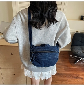 Rear view of a casual dark blue denim crossbody bag with adjustable canvas shoulder strap