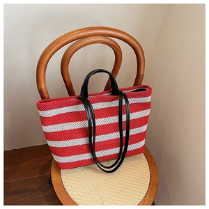 Vue détaillée du sac cabas rayé rouge et blanc avec des poignées en cuir noir de qualité