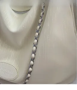 Detail of off-white shoulder bag with textured fabric and silver chain strap