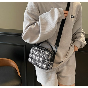 Detail of checkered crossbody bag with adjustable strap and small cartoon silhouettes