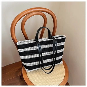 Vue détaillée d'un sac cabas à rayures noires et blanches avec poignées en cuir sur chaise