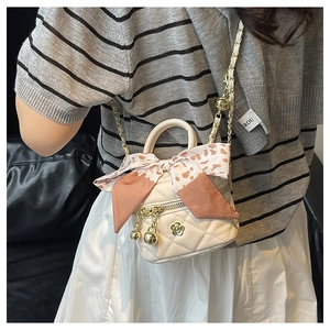 Detail showing cream quilted mini crossbody bag with gold chain and silk scarf wrap