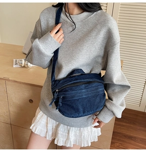 Detail shot of the navy denim crescent bag with zippers in a cozy lifestyle setting