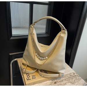 Detail of off-white Hobo bag featuring elegant pearl charms and gold chain accents