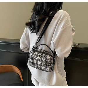 Detail view of black and white checkered crossbody bag with adjustable strap on person