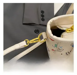 Detailed macro view of the premium gold-tone metal hook and buckle on the printed bucket bag