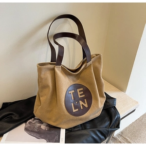 Detailed macro view of khaki canvas tote bag featuring brown leather trim and TE LN logo