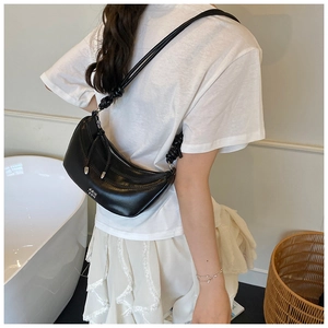 Détail du sac croissant en similicuir noir avec bandoulière nouée et logo argenté
