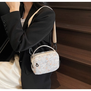 Detail of floral lace crossbody bag with orange flower pattern and woven brand tag