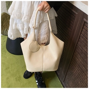 Detail of beige lychee texture leather tote bag with small round coin purse attachment