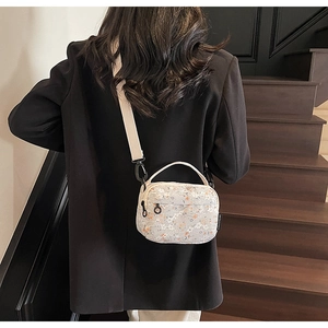 Detail of floral lace crossbody bag showing top handle and adjustable wide fabric strap