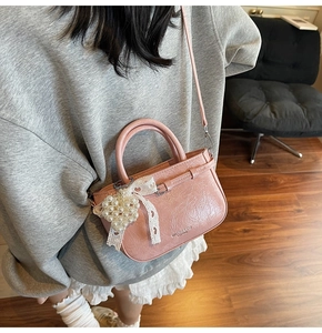 Detail der rosa Lackleder-Handtasche mit Perlenherz-Anhänger und Spitzenschleife
