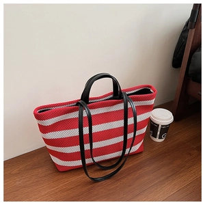 Détail du sac cabas en maille à rayures rouges et blanches avec poignées en cuir noir