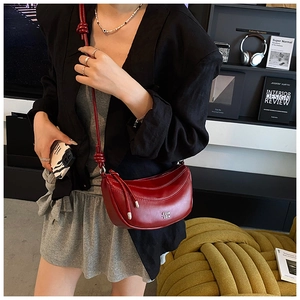 Détail du sac demi-lune rouge avec finition brillante et bandoulière à nœud réglable