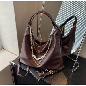 Detailed shot of coffee brown hobo bag with vintage texture, gold chain and pearls decor