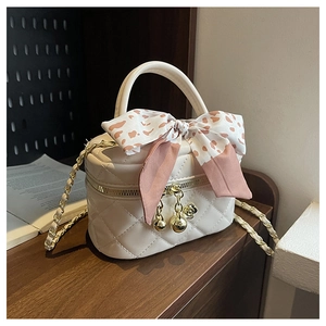 Detail of white quilted mini bag with gold ball charm and leopard print bow