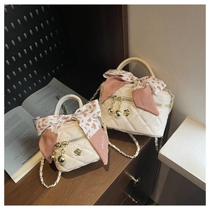 Detail of cream quilted mini box bags with floral bow ribbons and golden chain straps
