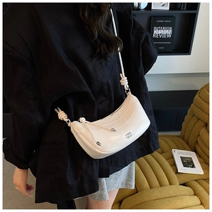 Détail du sac demi-lune en cuir souple blanc avec bandoulière à nœuds élégante