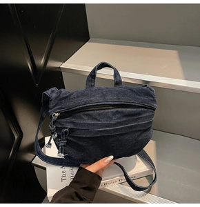 Detail view of retro blue denim crossbody bag with top handles and black zipper closure
