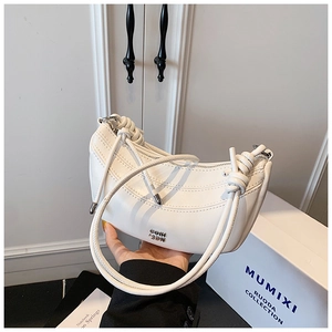 Gros plan du sac demi-lune en cuir blanc avec bandoulière nouée et logo en métal