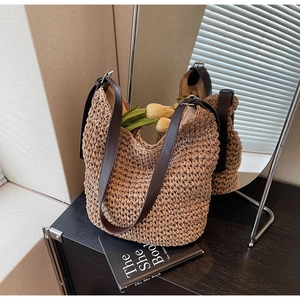 Close-up of handwoven straw tote with premium dark brown leather straps on a side table