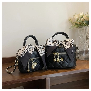 Detail of black quilted mini bags with gold ball charms and floral silk scarves