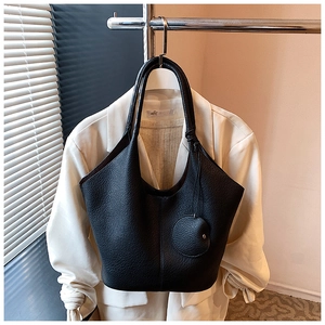 Detail of black litchi grain leather tote bag with circular pendant in a stylish setting