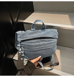Detail of blue denim tote bag with adjustable strap and zip closure on an art book