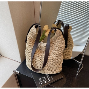 Detail of beige woven bucket bag with brown leather strap and adjustable buckle