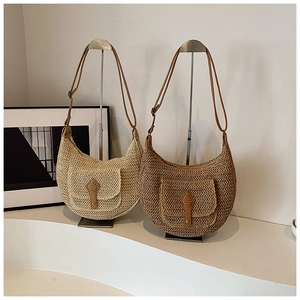 Detailed view of woven crescent bag featuring a front pocket and adjustable leather strap