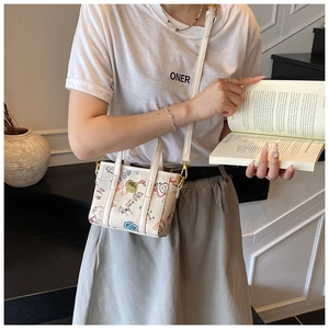 Close-up of mini white graffiti tote bag with colorful hand-drawn prints and gold logo