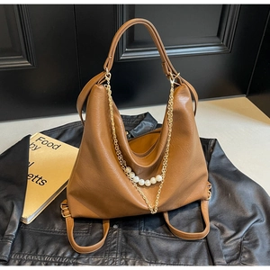 Detailed macro view of caramel brown tote bag with gold chain and white pearl accents