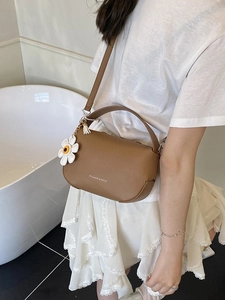 Brown litchi grain faux leather handbag with daisy charm shown on model's shoulder